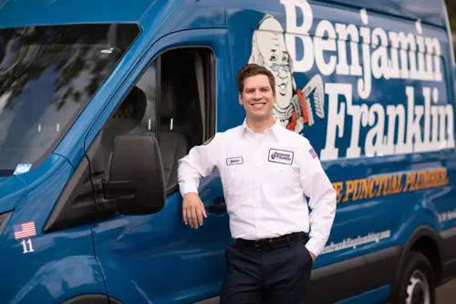 Wide angle closeup of Benjamin Franklin Technician, Pete, standing by his service van in front of a Pensacola FL home