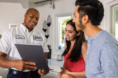 Benjamin Franklin Plumbing Tech, Trevor, speaking with two Pensacola FL homeowners as he goes over their plumbing quote on his tablet